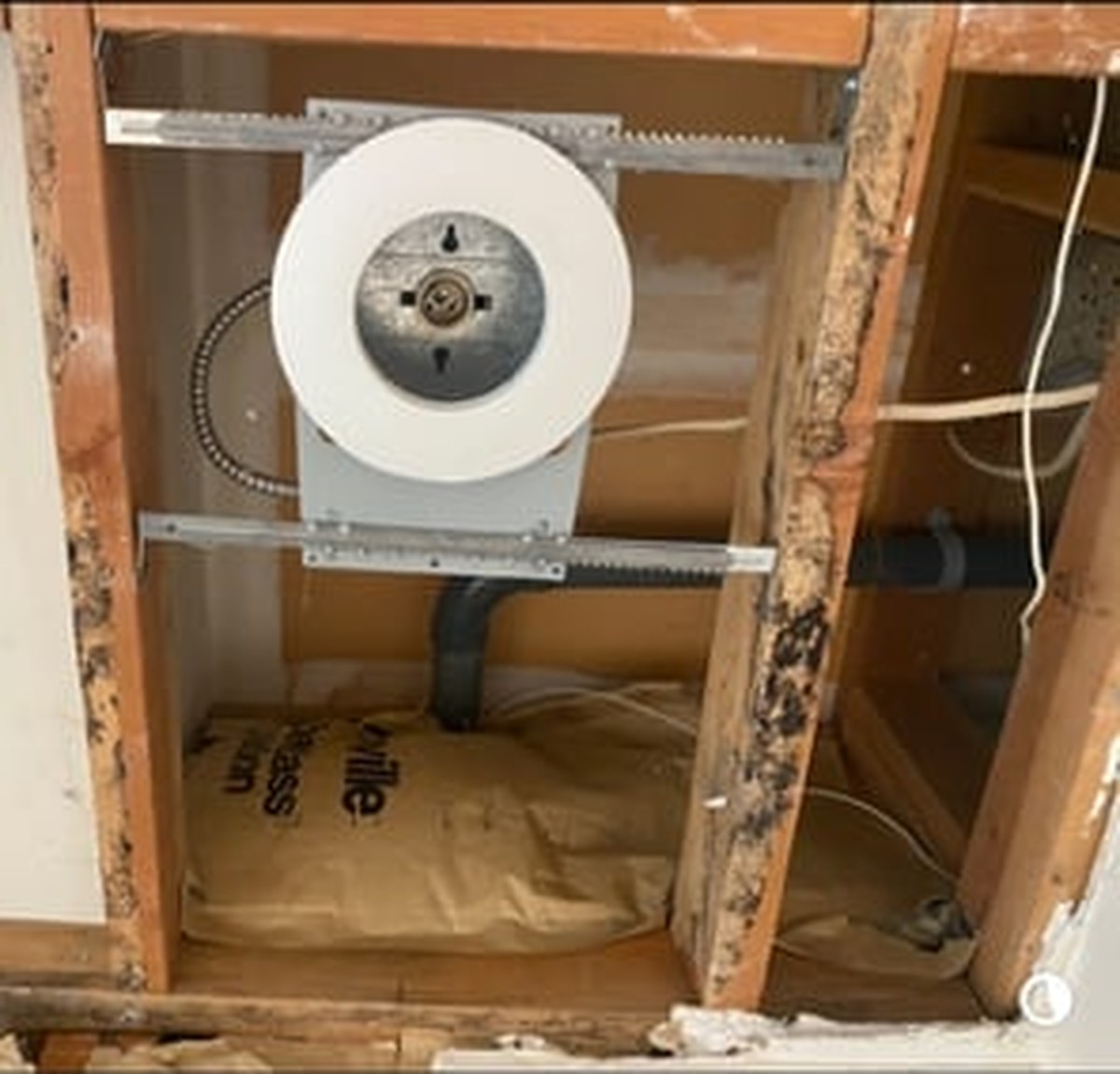 White ventilation duct with motor installed in wooden wall cavity during construction